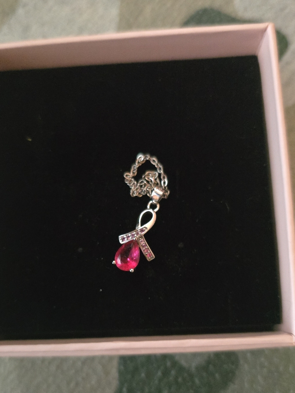 breast cancer awareness ribbon pendant attached to a silver-toned cable chain, a